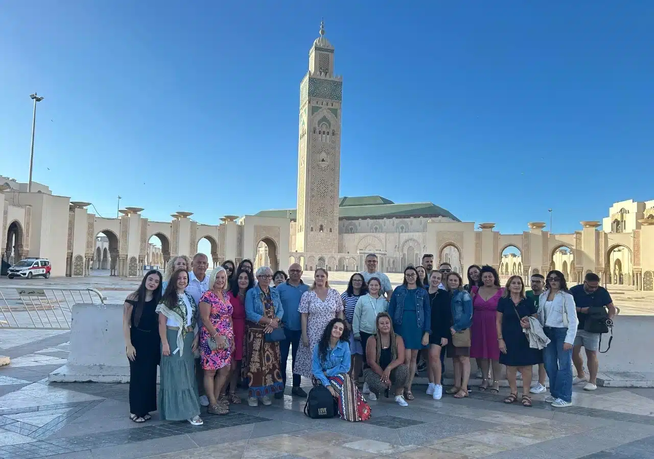 Tour group standing on the plaza of the Hassan II Mosque in Casablanca with the minaret in the background, illustrating a typical sightseeing stop.