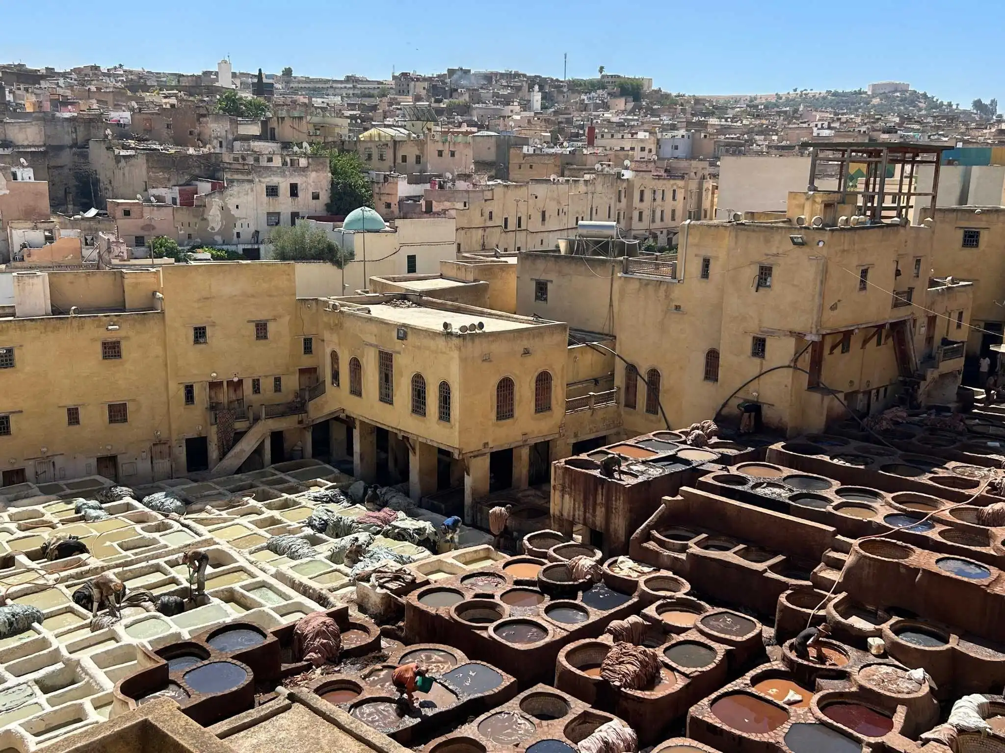 Overlook of the Chouara leather tannery in Fes with stone dye pits and Medina rooftops—classic stop when deciding trip length in Morocco.