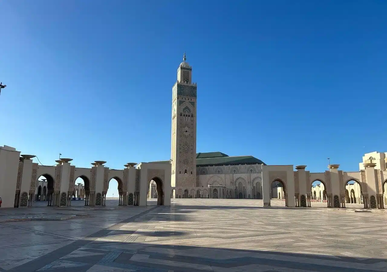 Wide view of the Hassan II Mosque and open marble plaza under a bright blue sky in Casablanca, ideal for a short city tour.