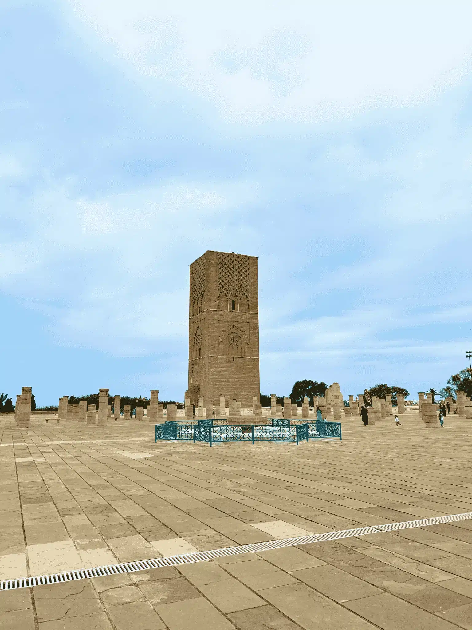 Wide view of Rabat’s Hassan Tower and the pillar-studded esplanade under a soft blue sky.