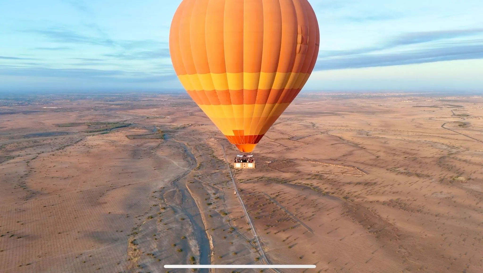 Orange hot-air balloon floating above desert plains near Marrakech—bucket-list experience to add when planning days in Morocco.